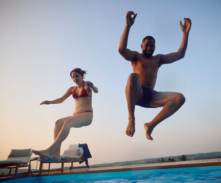 Man and woman are jumping into the pool