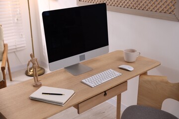 Wooden desk with computer and stationery at home office, closeup. Interior design