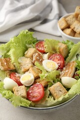 Delicious salad with croutons, chicken, quail eggs, tomato and cheese on grey table, closeup