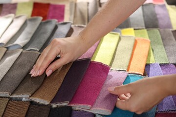 Woman choosing fabric among different samples indoors, closeup
