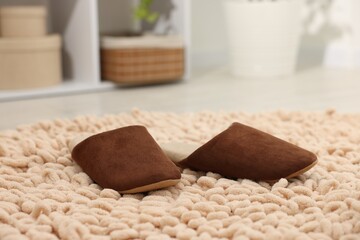 Stylish brown slippers on soft carpet indoors, closeup