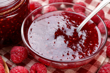 Sweet raspberry jam in glassware and berries on table, closeup