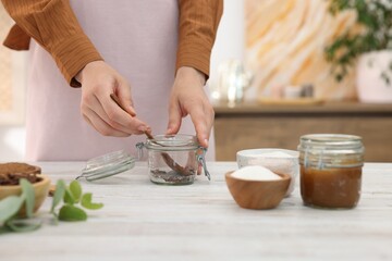 Woman making natural body scrub at white wooden table, closeup