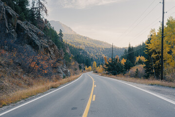 Winding mountain road lined with colorful fall foliage in morning light