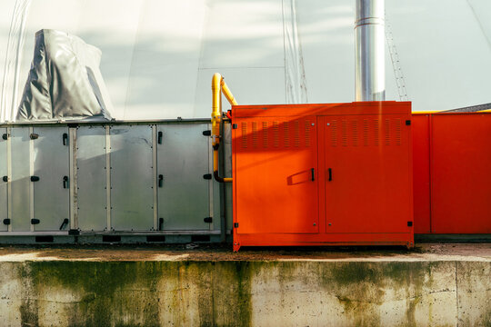 Red industrial generator and metal units with yellow pipes