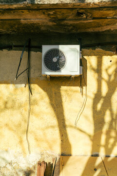 Wall-mounted air conditioning unit on yellow exterior wall