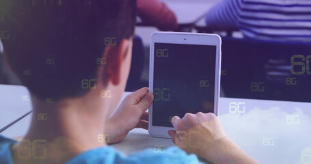 Tapping boy wearing blue T-shirt tapping white tablet screen at school classroom, with 6G symbols