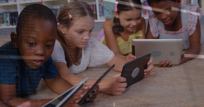Lying group of four children using touchscreen tablets on wooden library floor, with bookshelves