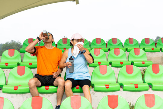 Mature couple sits on a bleacher while taking a break
