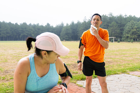 Mature man wipe sweat from his neck while chatting with his wife