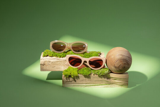 Stylish sunglasses are creatively arranged on wooden logs adorned