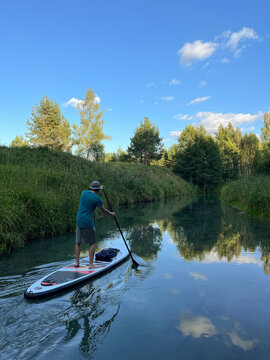 Man paddling upstream on green forest creek