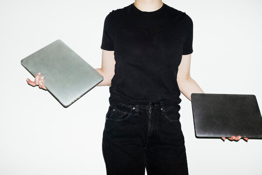 Person holding two silver laptops in office with hard direct flashligh