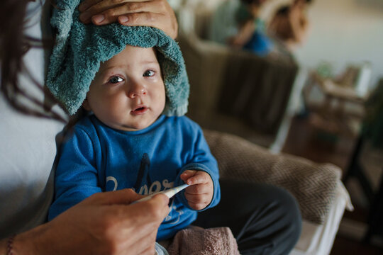 Child With a Fever Resting on a Parent's Lap at Home