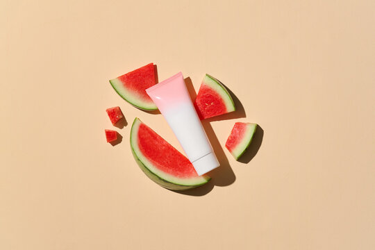 Cosmetic tube with fresh watermelon slices on a beige background