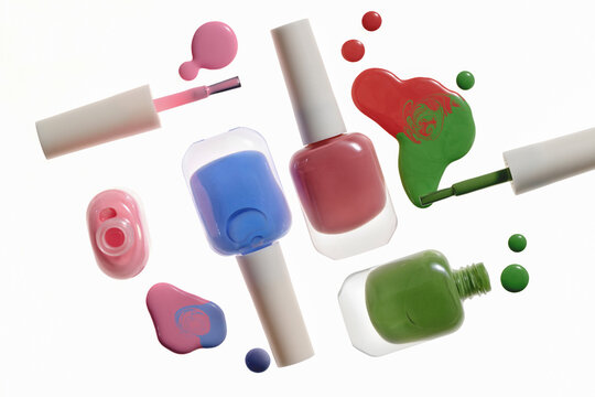 Vibrant nail polish bottles and spills on white background