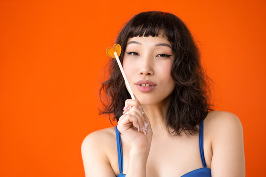 Сute asian curly woman with lollipop