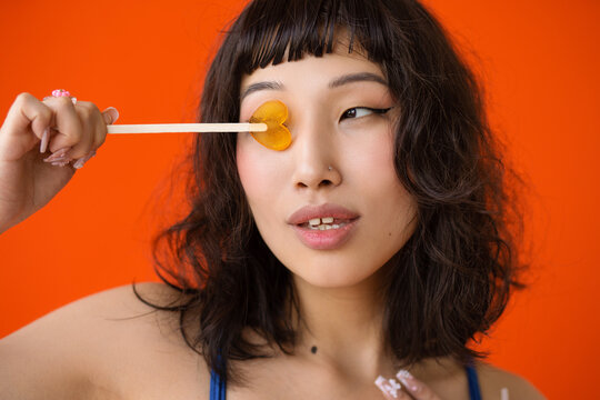 Сute asian curly woman with lollipop