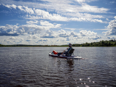 Man paddling sup board with chair on river