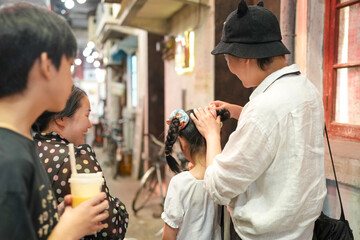 Inside a shopping mall recreating an old town street, a Chinese family strolls as women in their thirties chat by wooden facades, lanterns, and shopfronts that echo history. Shanghai, China. Spring.