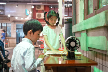 Inside an old-town mall, a Chinese family enjoys the day: a one-year-old in a stroller, kids under...