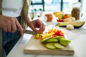 Close up of a woman chopping fresh vegetables on modern kitchen counter