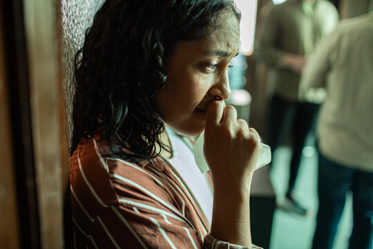 Upset woman crying while holding tissue after therapy indoors