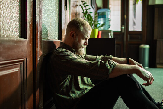Depressed man sitting alone on floor feeling sad and stressed