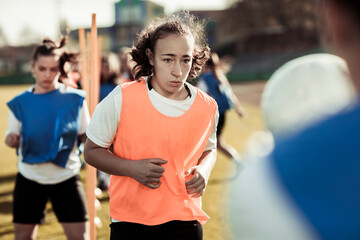 Teen girl practicing soccer drills during team training at stadium