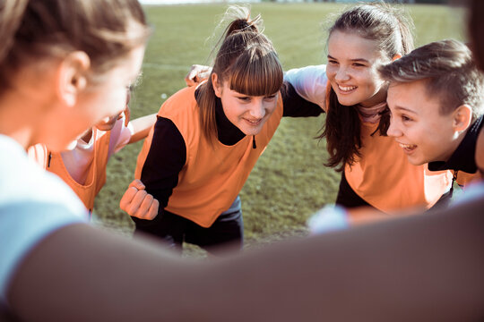 Teen soccer team huddling before match on outdoor field