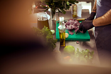 Chef slicing red onions on cutting board in professional kitchen