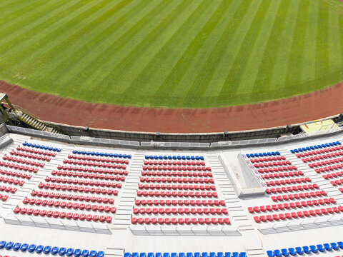 Empty Stadium Seats and Running Track Around Green Field