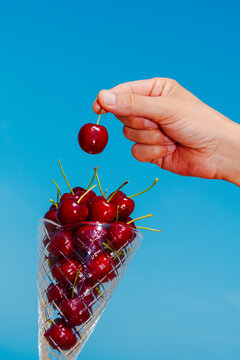 man taking a cherry from a conical glass