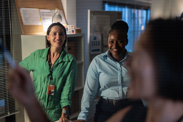Two smiling women in an office setting during late working hours