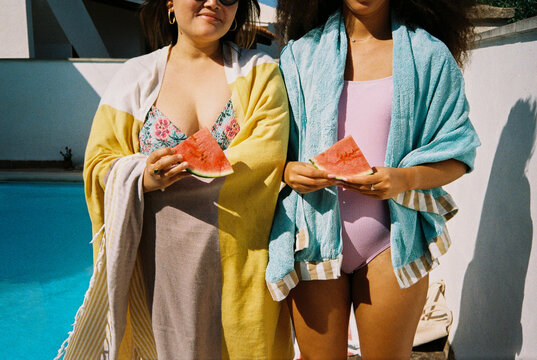 Women with watermelon slices by the pool