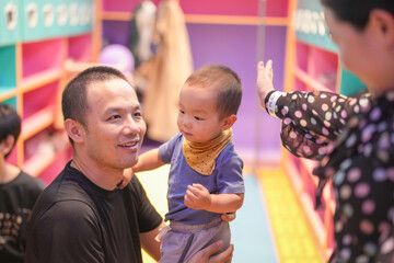 Chinese children and adults enjoy talking in a colorful locker room at an indoor play area. Hongkou District, Shanghai, China. Spring.