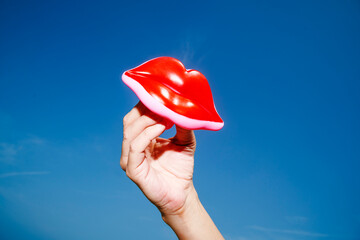 man holds a pair of red plastic lips in his hand