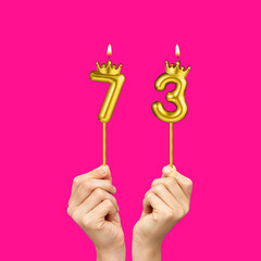 Hands holding number shaped candles - Birthday number 73