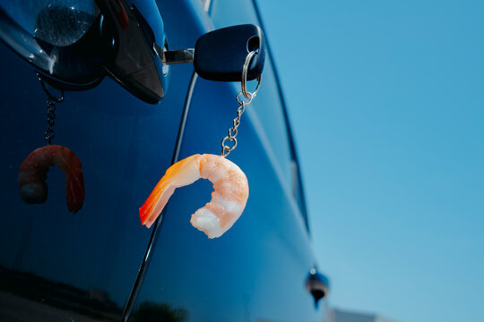 peeled shrimp keychain dangles from the key of a parked car