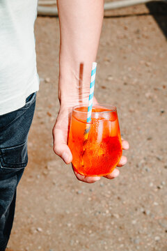 man with an aperol spritz in his hand on the beach