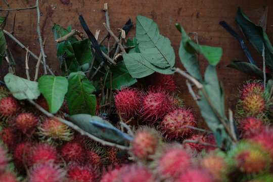 Fresh Rambutan Fruit and Leaves Arranged on a Wooden Surface