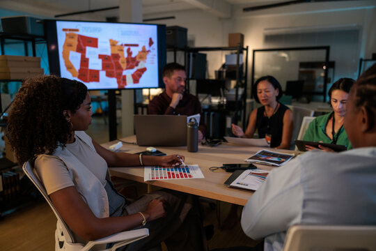Team analyzes map and charts in office meeting late at night