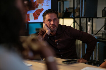 Man contemplates data map in dimly lit meeting room late at night