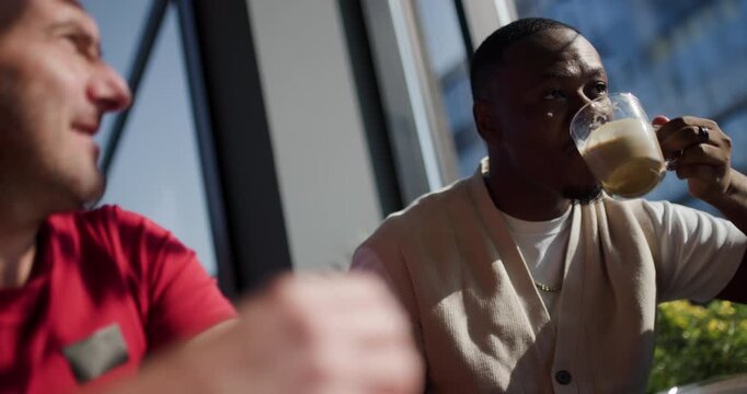 Two Male Friends Enjoy Coffee and Conversation at a Cafe, Sharing Laughter and Camaraderie