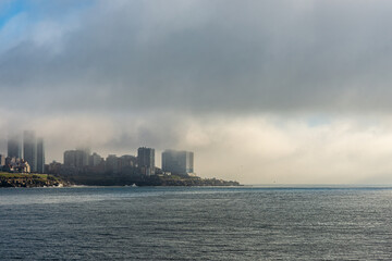 Morning view of Mar del Plata city with buildings partially covered by fog, facing the Atlantic Ocean. Urban and coastal scenery with natural atmosphere.