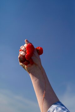 Strawberries splattered in the sky, juice running down the hand 