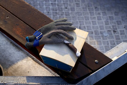 Knife, gloves and a box of oysters on a wooden surface