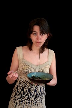 Woman enjoying noodles while wearing a stylish knitted top