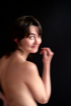 Woman with short hair poses gracefully against a dark background