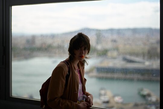 Woman Gazing out a City Window With a View of the Waterfront